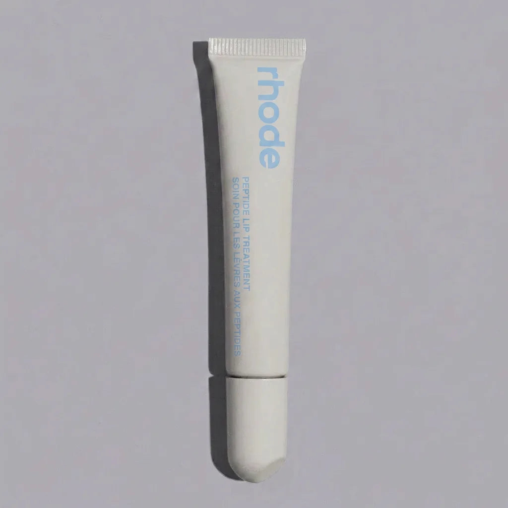 Tube of 'rhode' lip treatment on a gray background