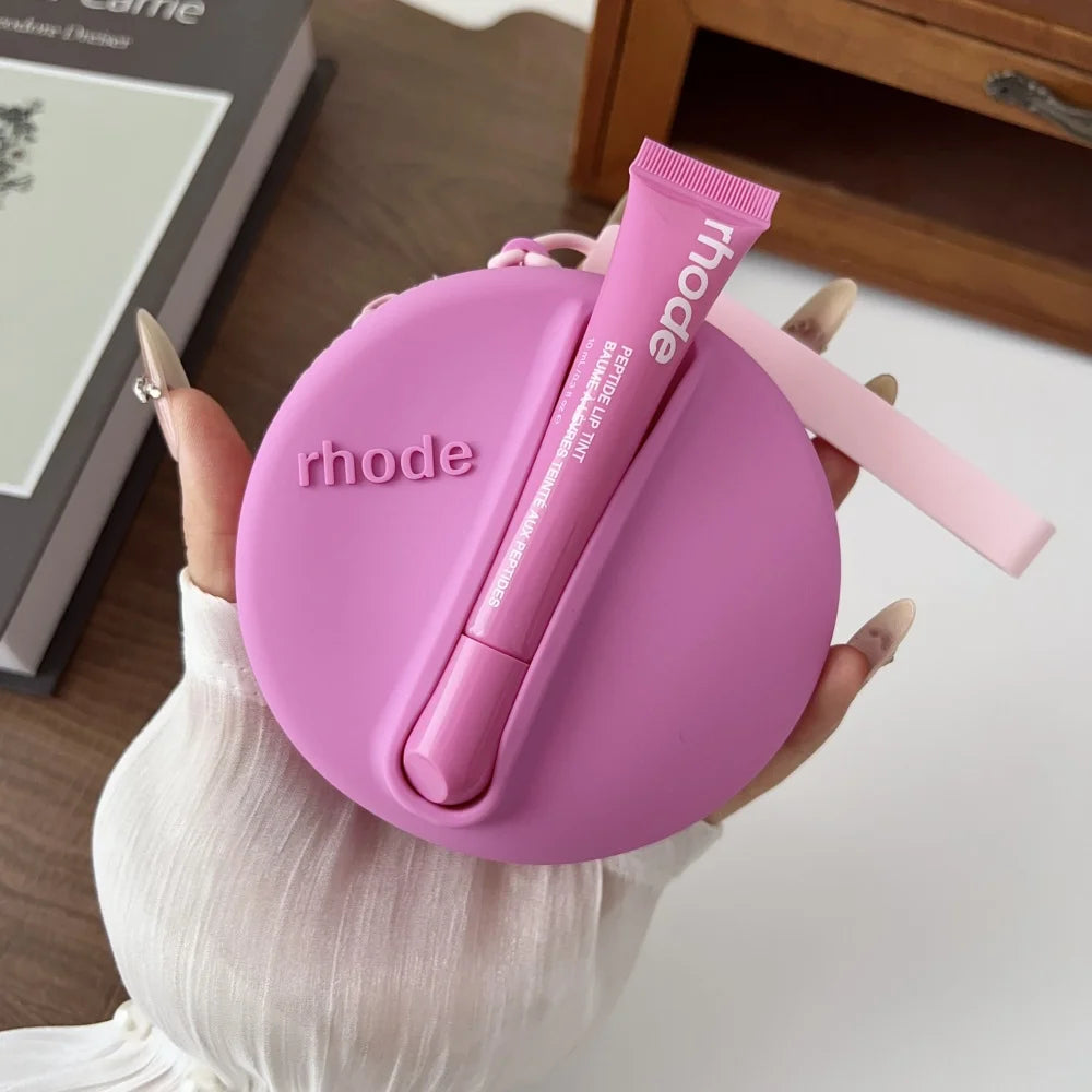 Pink 'rhode' case with a lip balm held by a hand on a light background