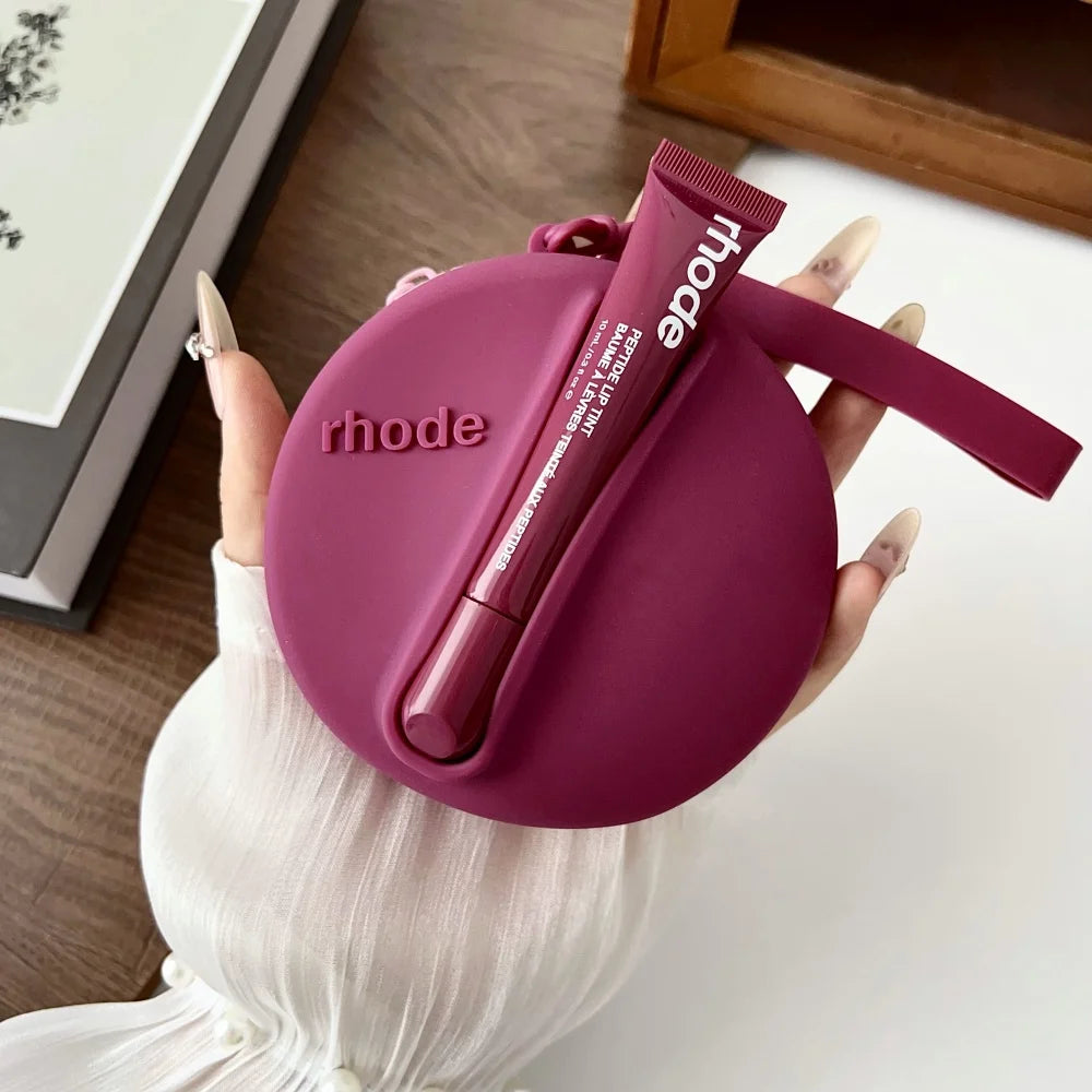 Purple case with a lip balm labeled 'rhode' held by a person.