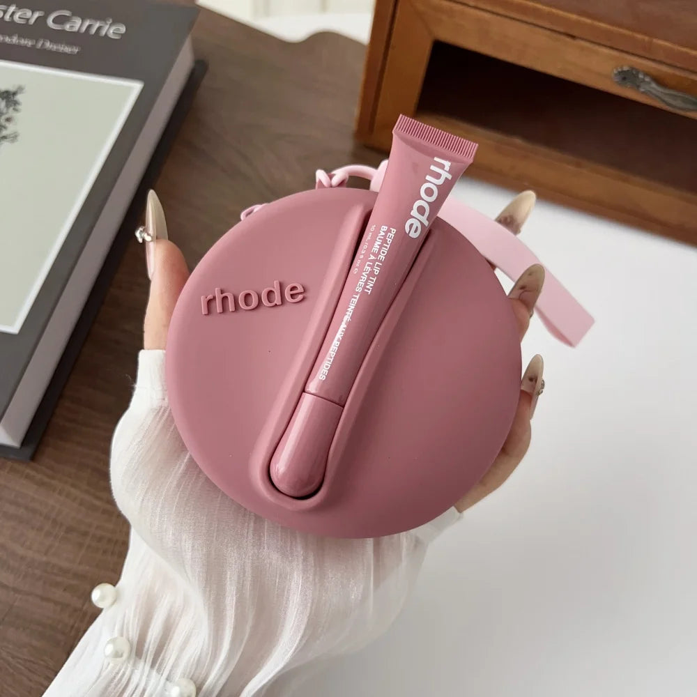 Pink 'rhode' case with a matching lip balm held by a hand on a wooden surface.