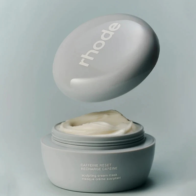 Rhode Caffeine Reset Recharge Caffeine Scraping Cream Mask in a matte gray jar with the lid floating above, showing the cream inside, on a matching gray background.