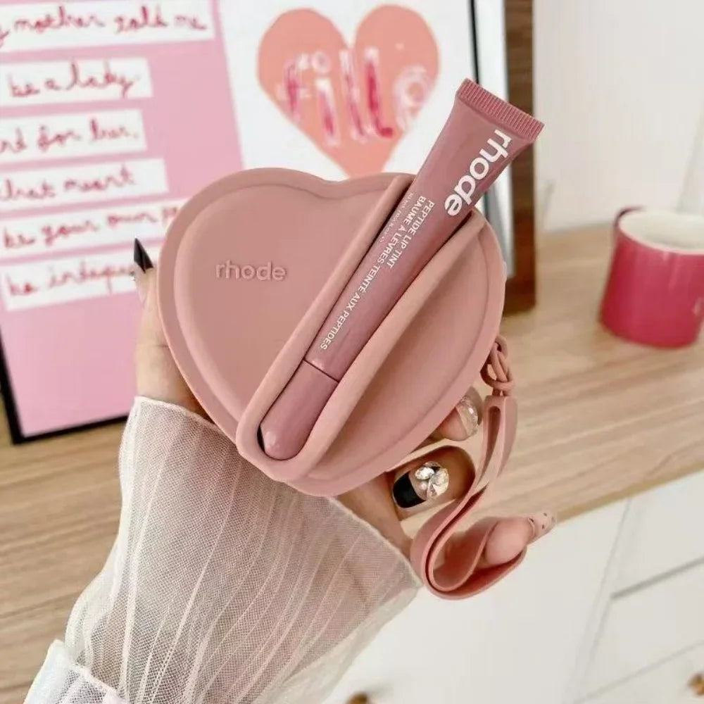 Heart-shaped pink case with a lip balm labeled 'rhode' held by a person.