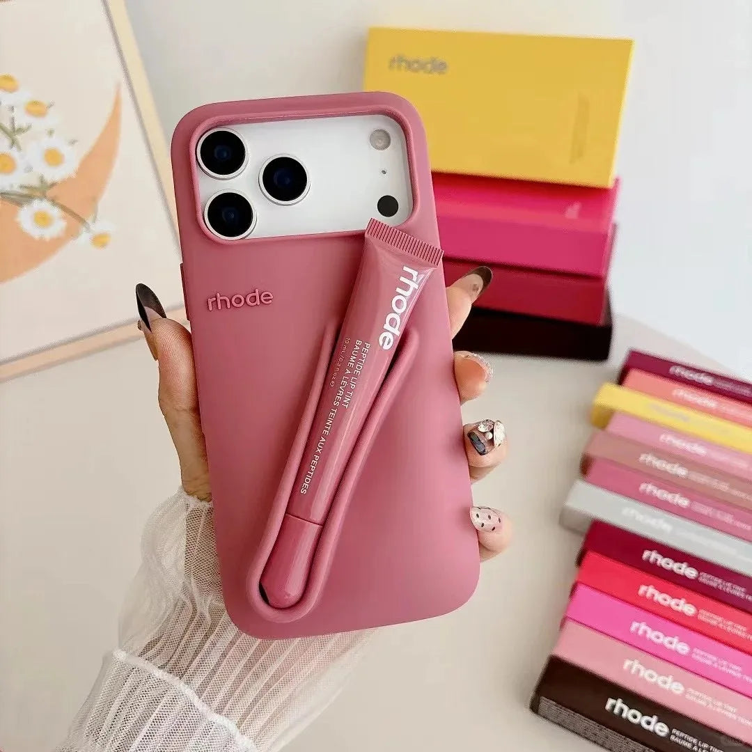 Pink phone case with 'rhode' branding held by a hand, with more cases in the background.
