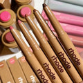Set of Rhode makeup pencils with pink caps on a white background