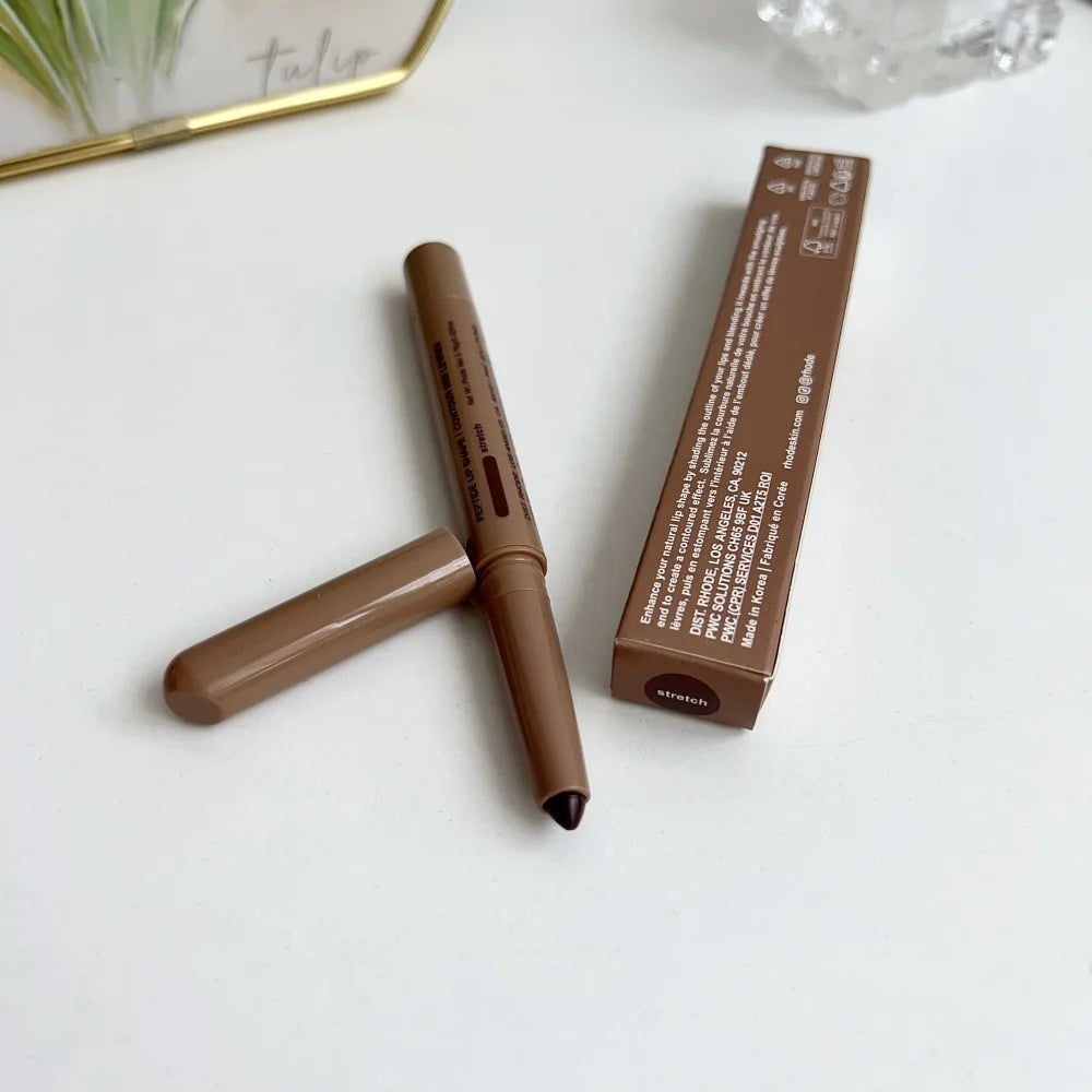 Brown makeup pencil with cap and packaging on a white surface