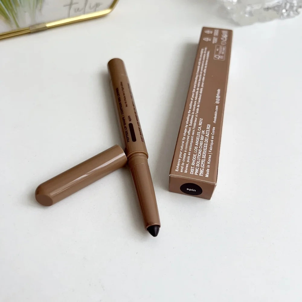 Brown makeup pencil with black cap and its packaging on a white surface