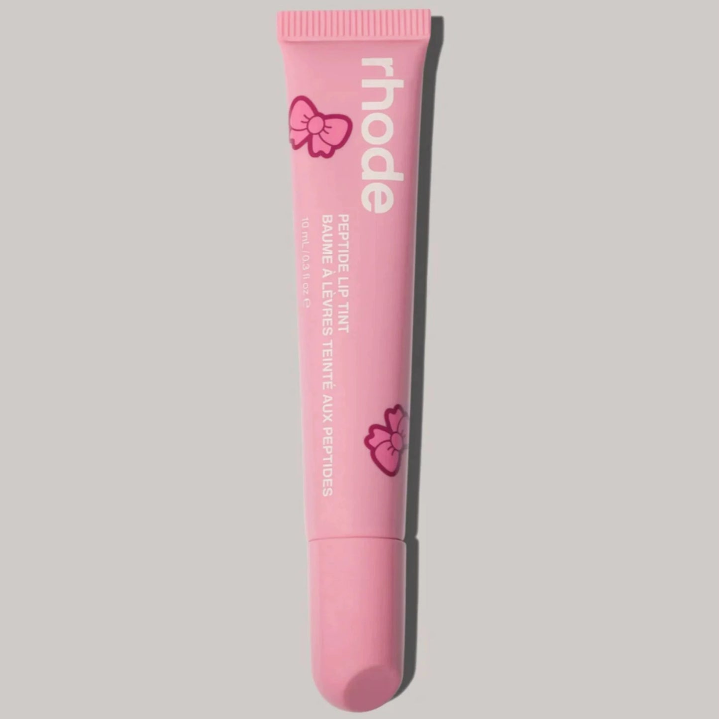 Pink lip balm tube with 'rhode' branding on a gray background