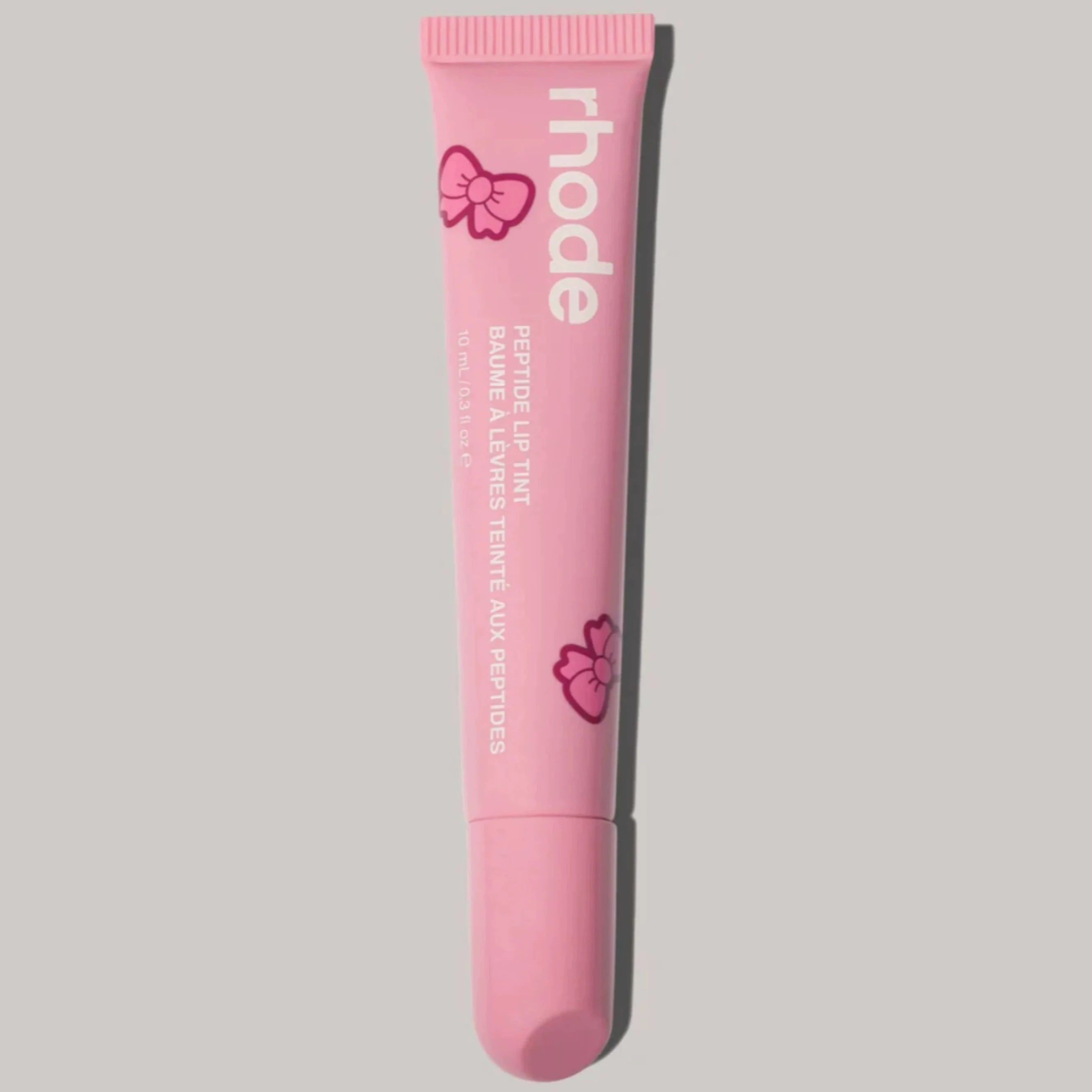 Pink lip balm tube with 'rhode' branding on a gray background