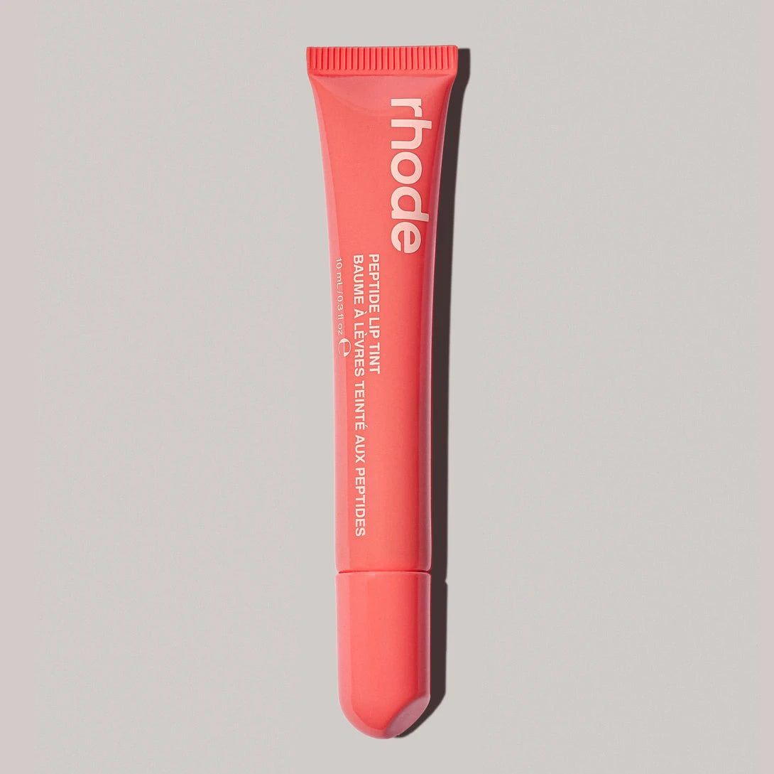 Pink lip balm tube with 'rhode' branding on a gray background