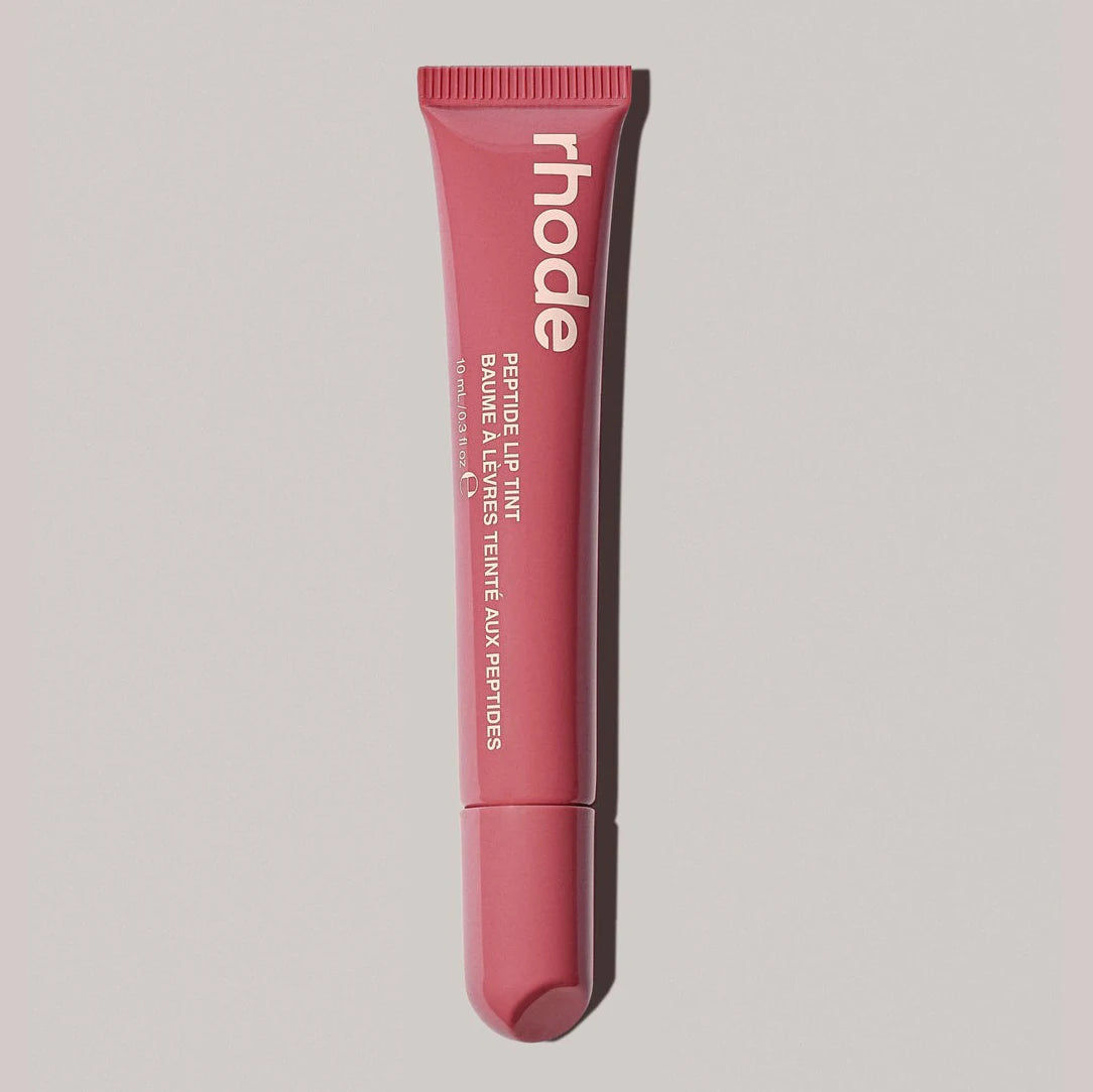 Pink lip balm tube with 'rhode' branding on a light gray background