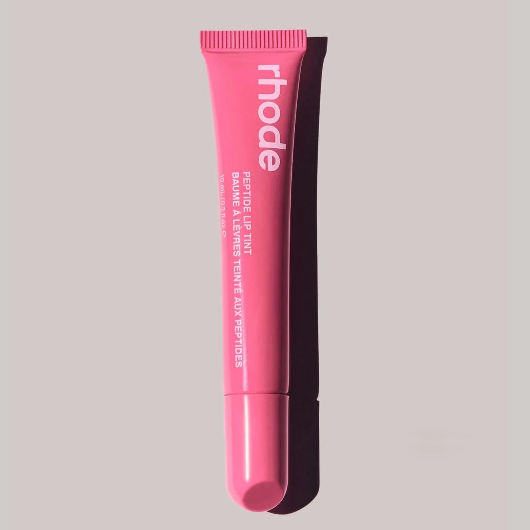 Pink lip balm tube with 'rhode' branding on a gray background