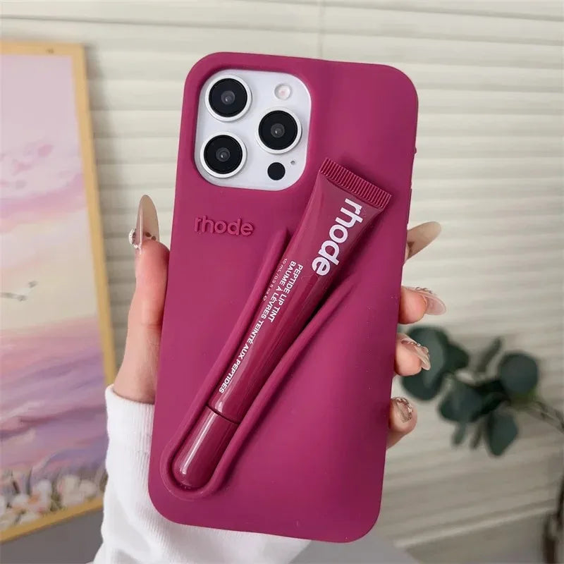 Pink phone case with a built-in lip balm held by a hand against a neutral background