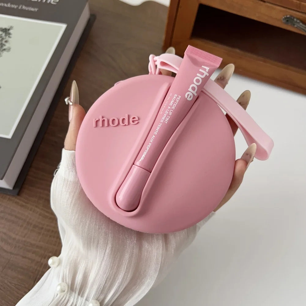 Pink 'rhode' case with a matching tube held by a hand on a light surface.