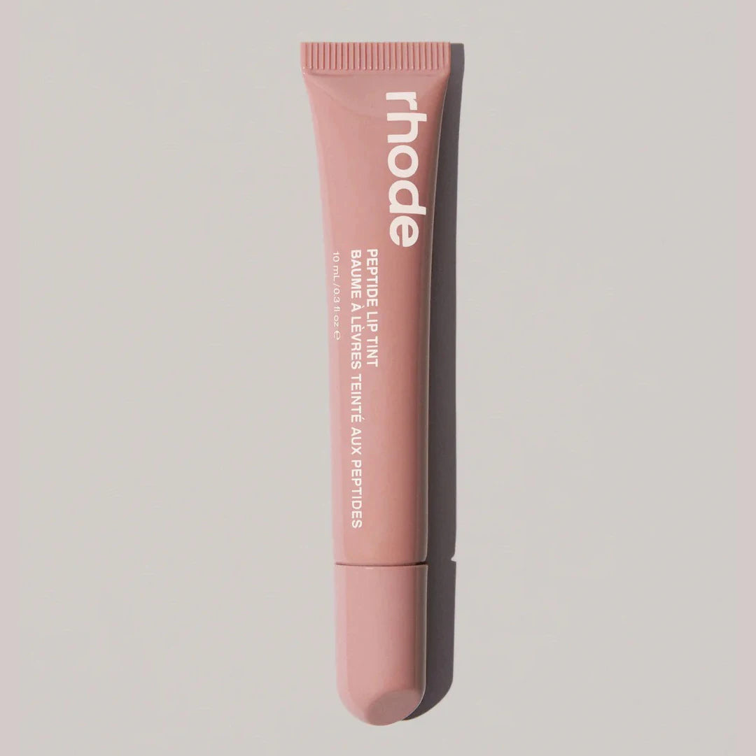 Pink lip balm tube with 'rhode' branding on a light gray background