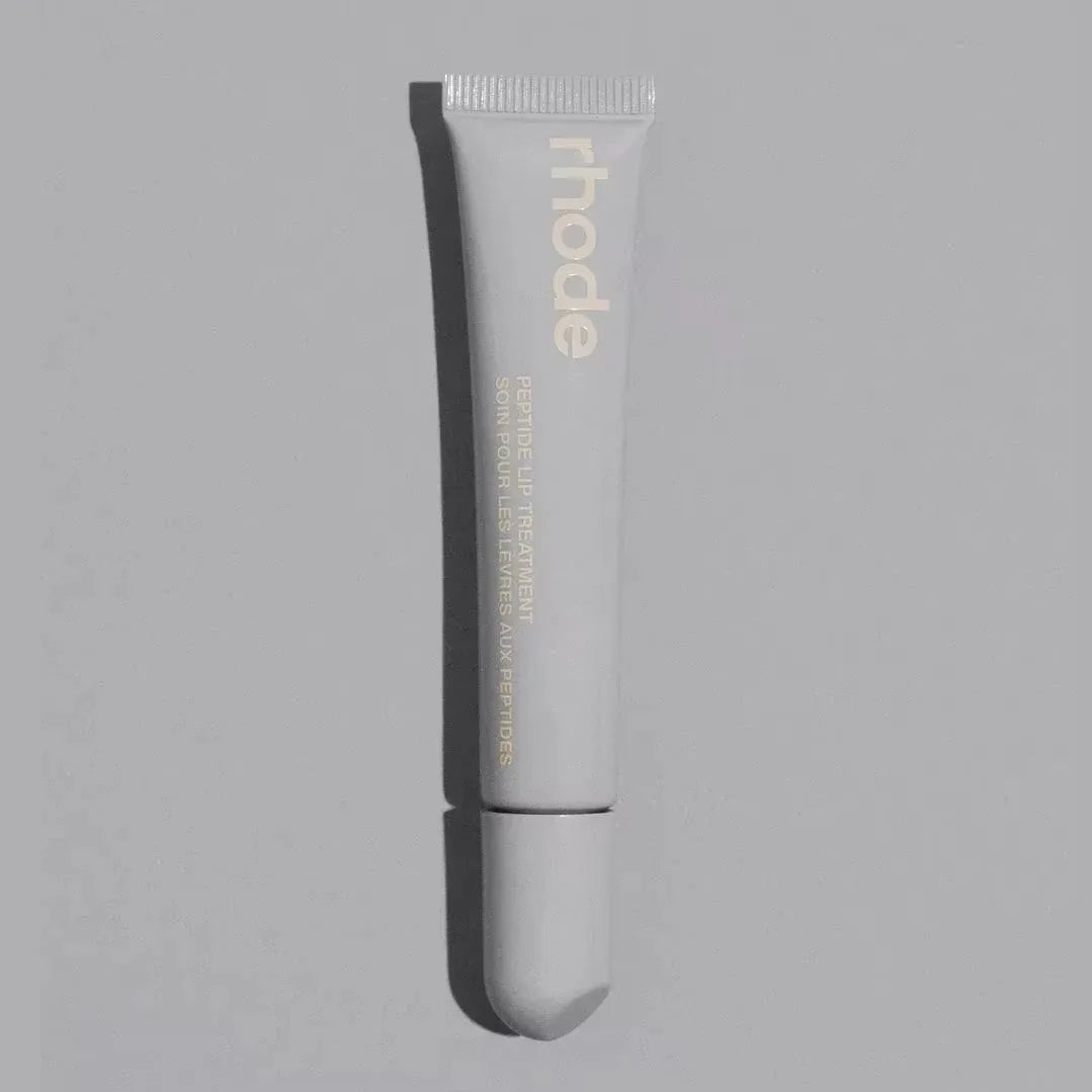 Skincare tube labeled 'rhode' on a gray background salted caramel 