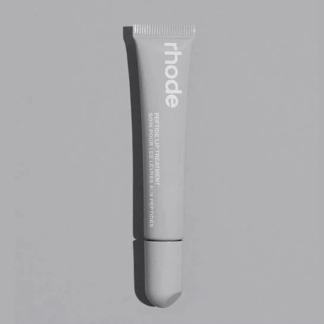 Tube of 'rhode' lip treatment on a gray background