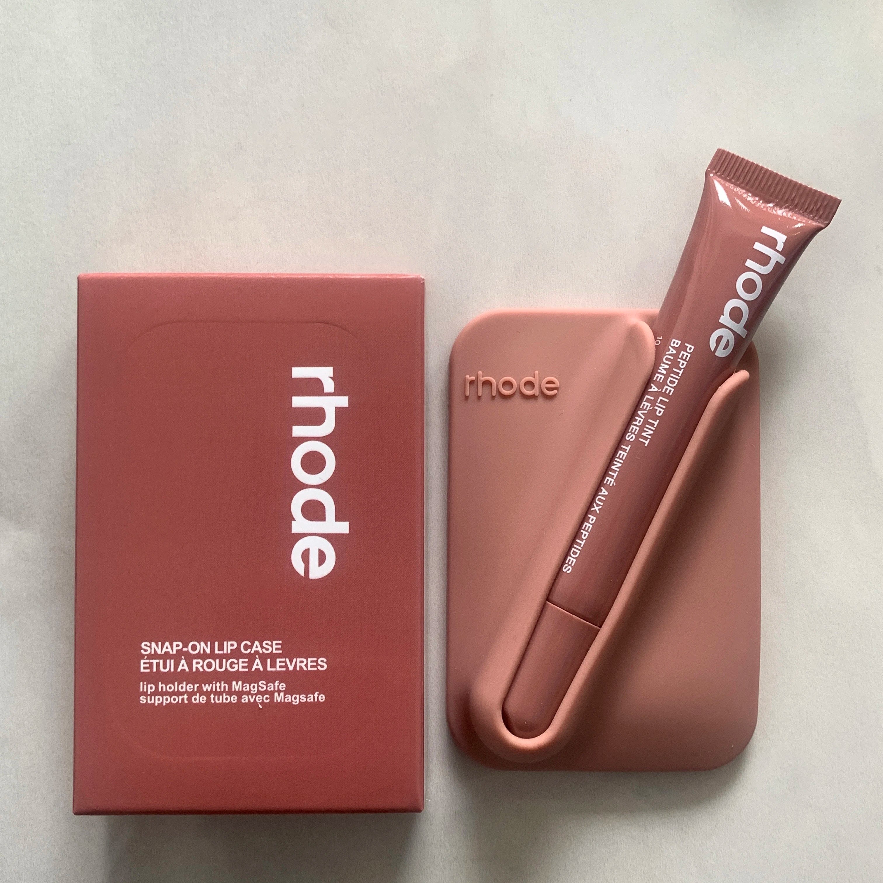 Pink lip case and tube with 'rhode' branding on a light gray background