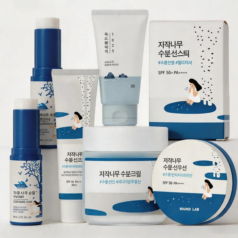 A set of skincare products from ROUND LAB featuring white and blue packaging with Korean text, including a bottle, tube, jar, and box, arranged on a white background.
